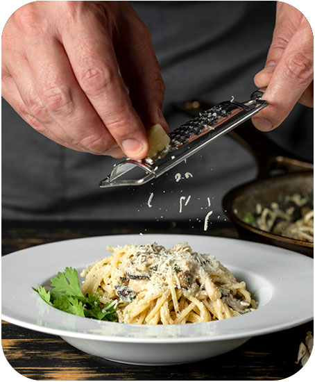 Chef grating cheese on pasta